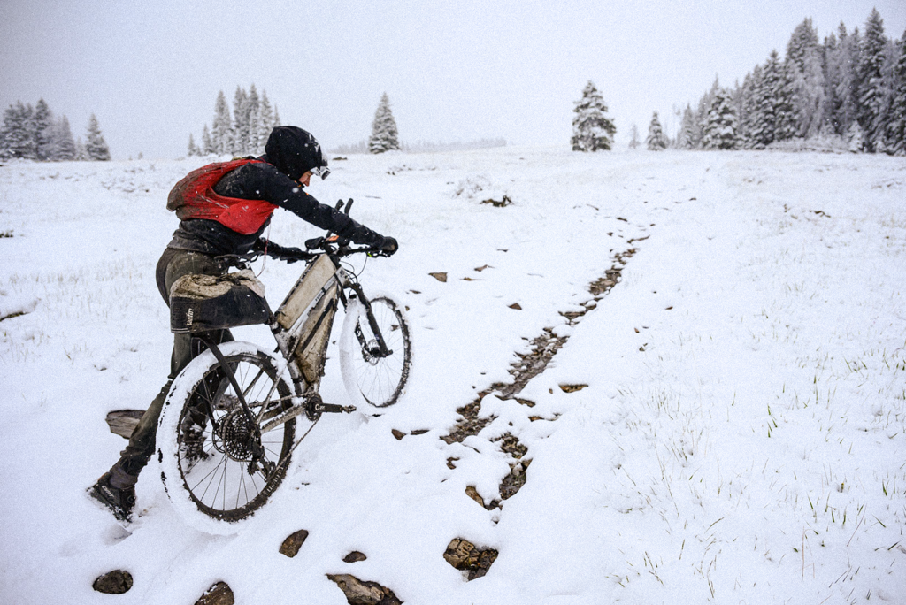 A cyclist hiking through snowy conditions in the Tour Divide race with Tailfin equipment on their bike