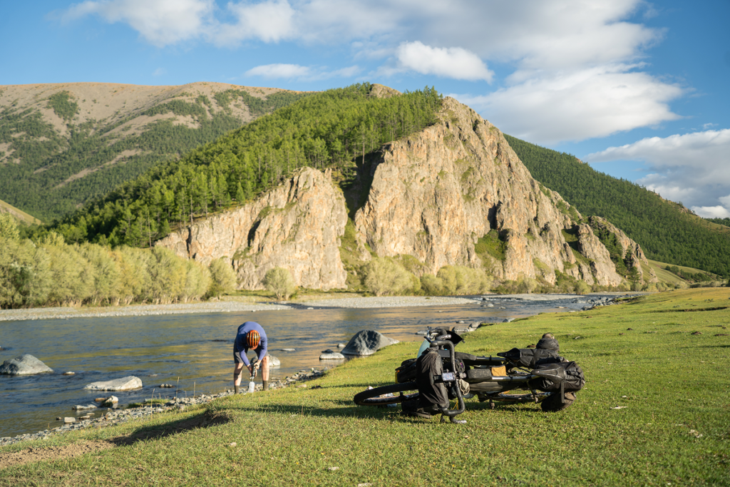 Tailfin bikepacking bags on an adventure bicycle by a scenic mountain river.