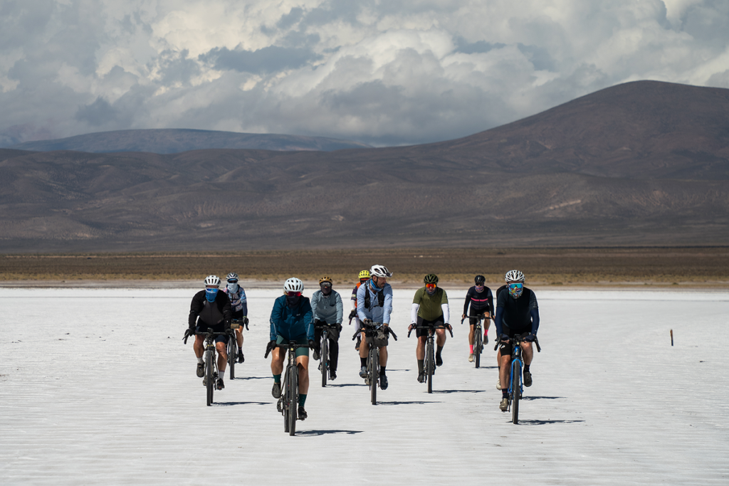 Cyclists ride across vast salt flats equipped with Tailfin bikepacking gear.