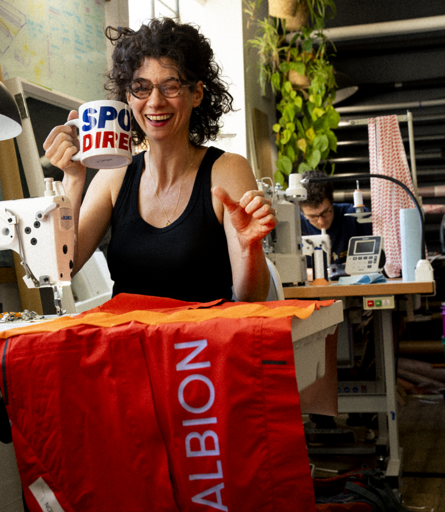 A designer sews red Albion fabric on a sewing machine in the Tailfin workshop.