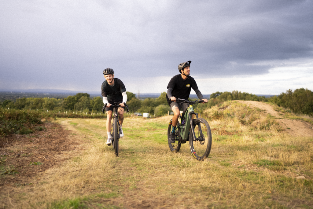 Tailfin gravel and MTB riders cycling side-by-side on a scenic hillside trail.