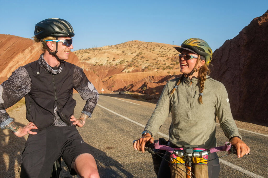 Two cyclists on a Tailfin bikepacking adventure through a scenic desert mountain landscape.